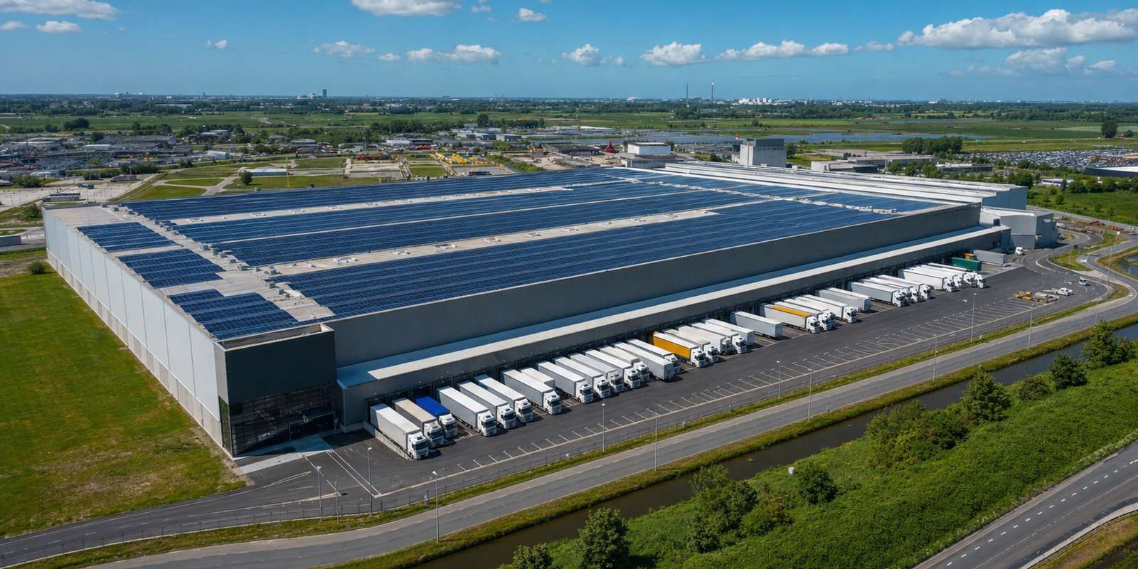 Distributiecentrum met zonnepanelen op het volledige dak en vrachtwagens aan de laadperrons