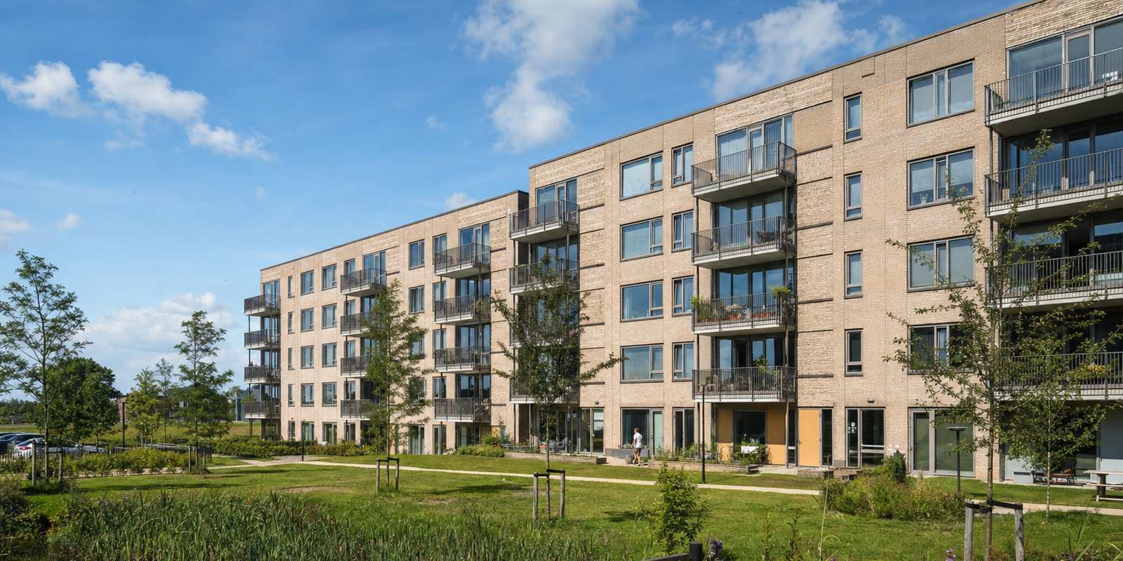 Nieuw opgeleverd sociale-huurcomplex met bakstenen gevel en balkons